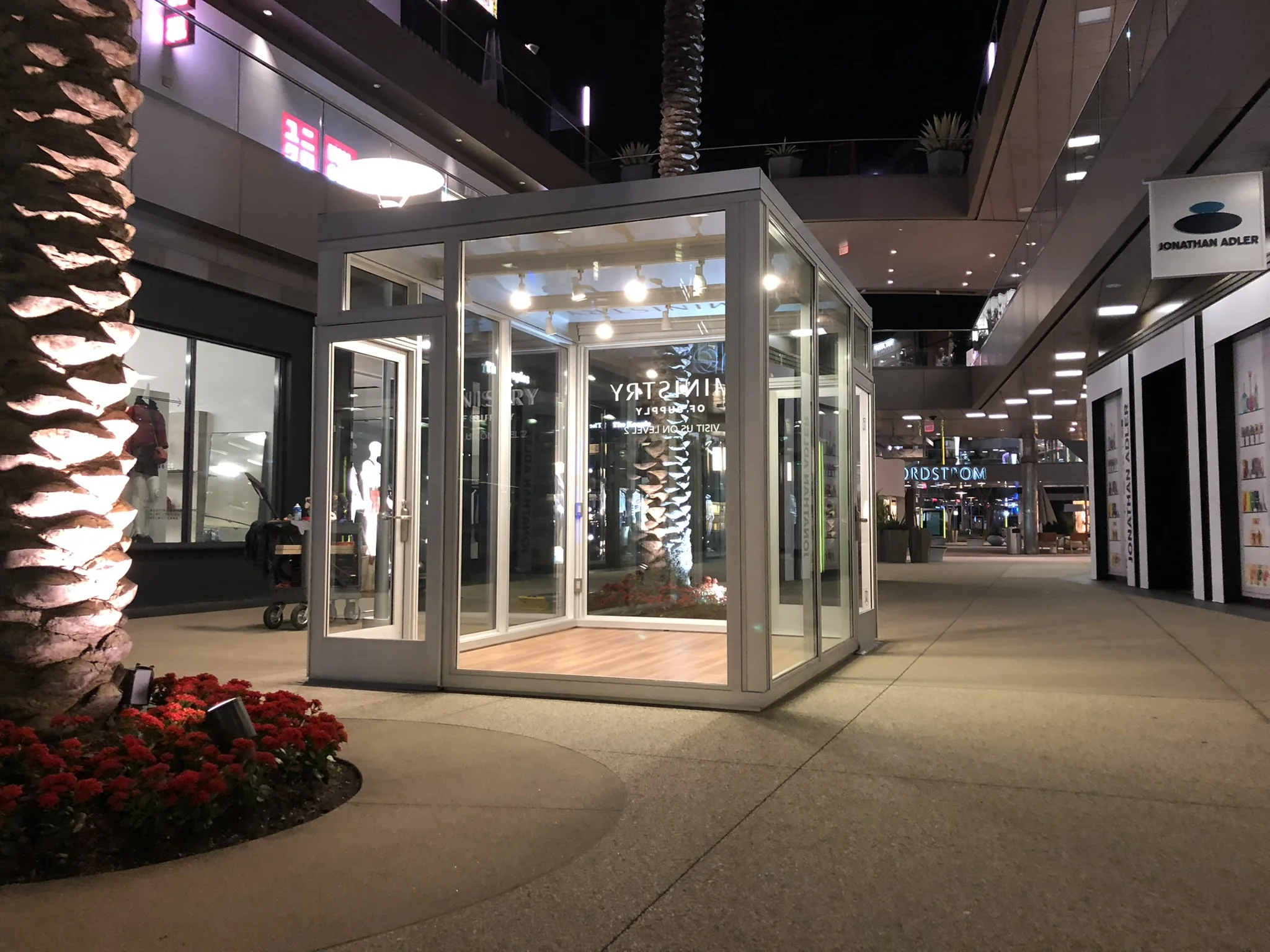 Illuminated glass storefront in a commercial plaza at night