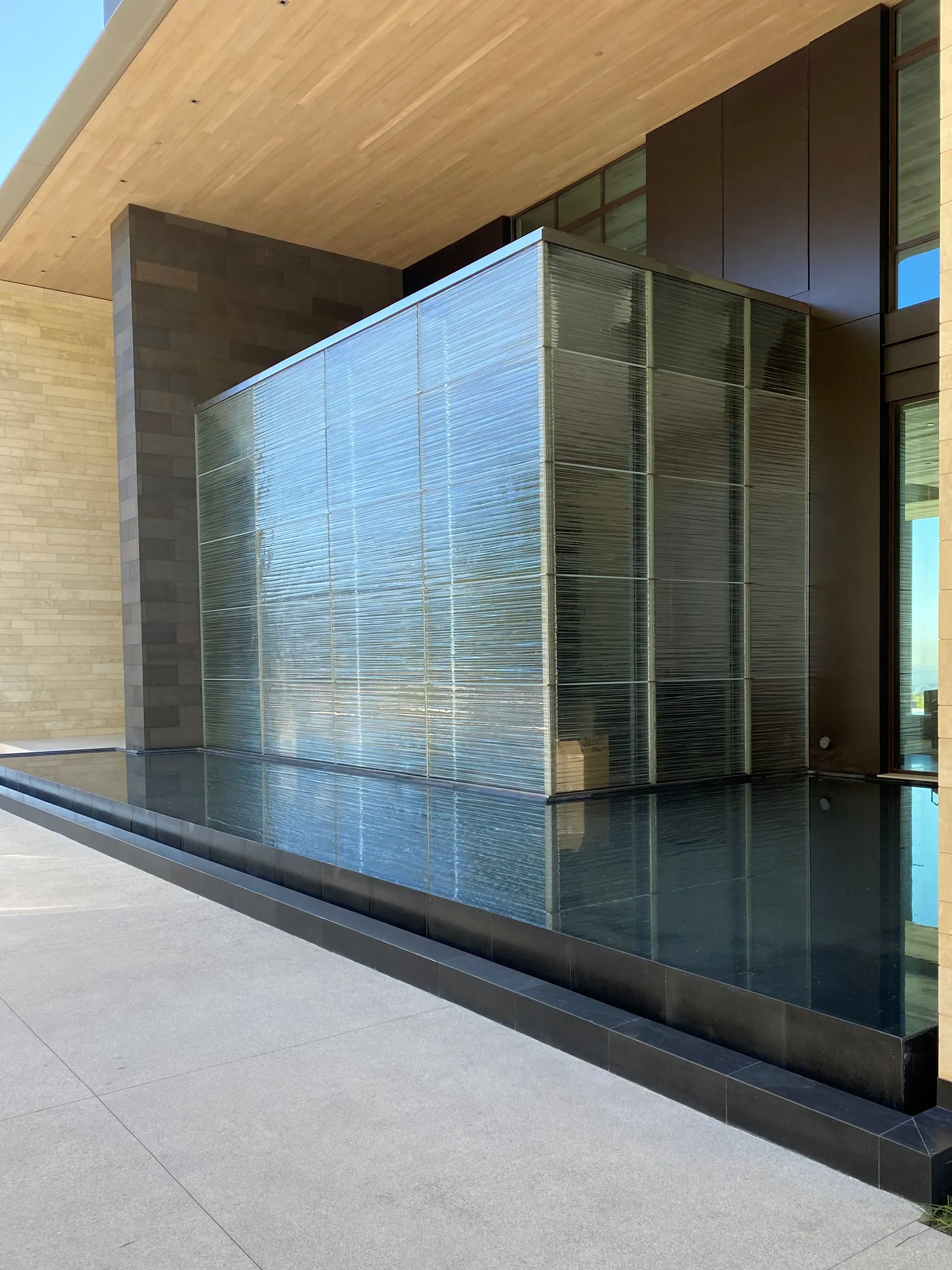 Textured architectural glass volume set in a reflecting pool