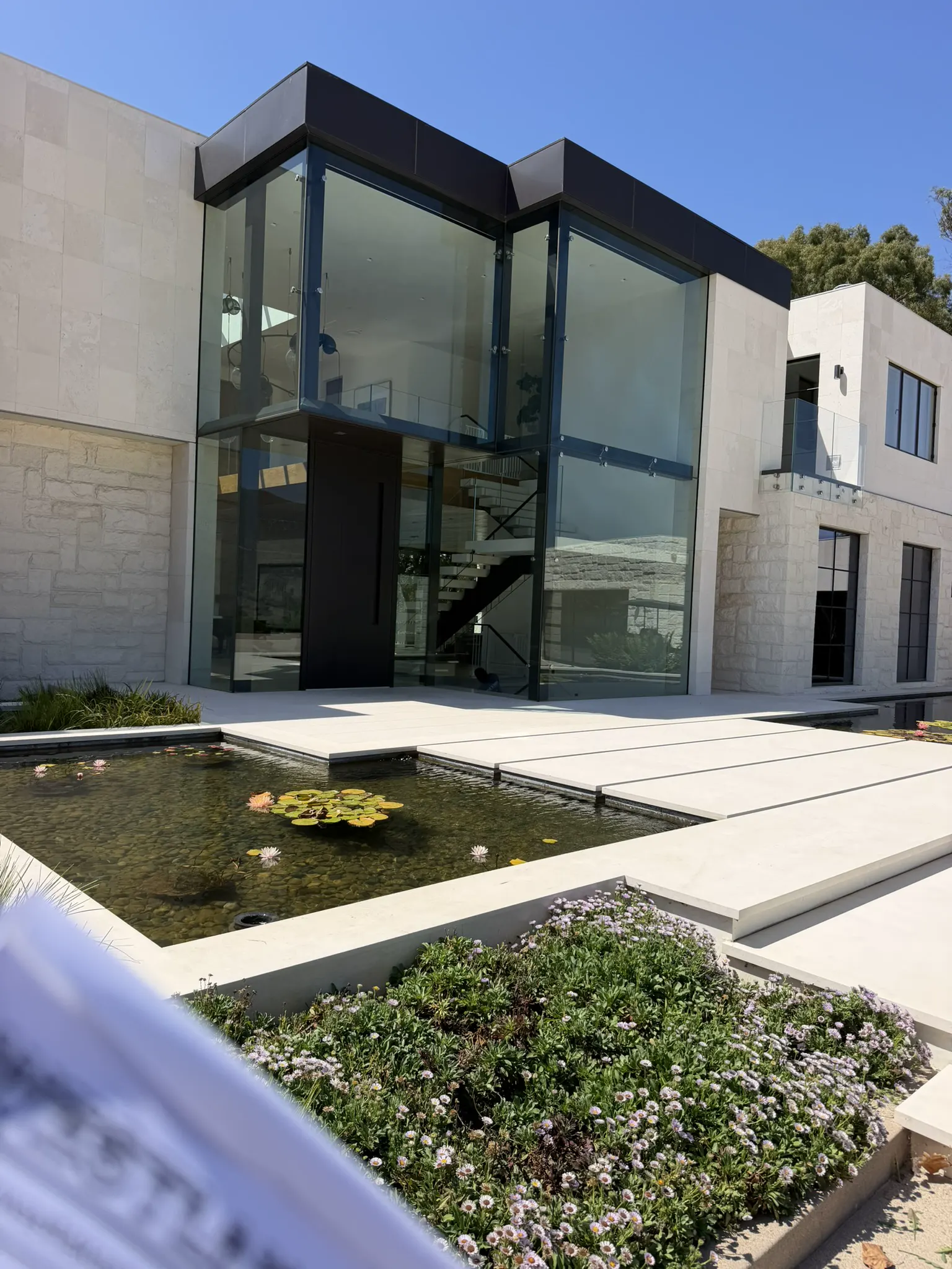 Two-story glass facade with a reflecting pool in the foreground
