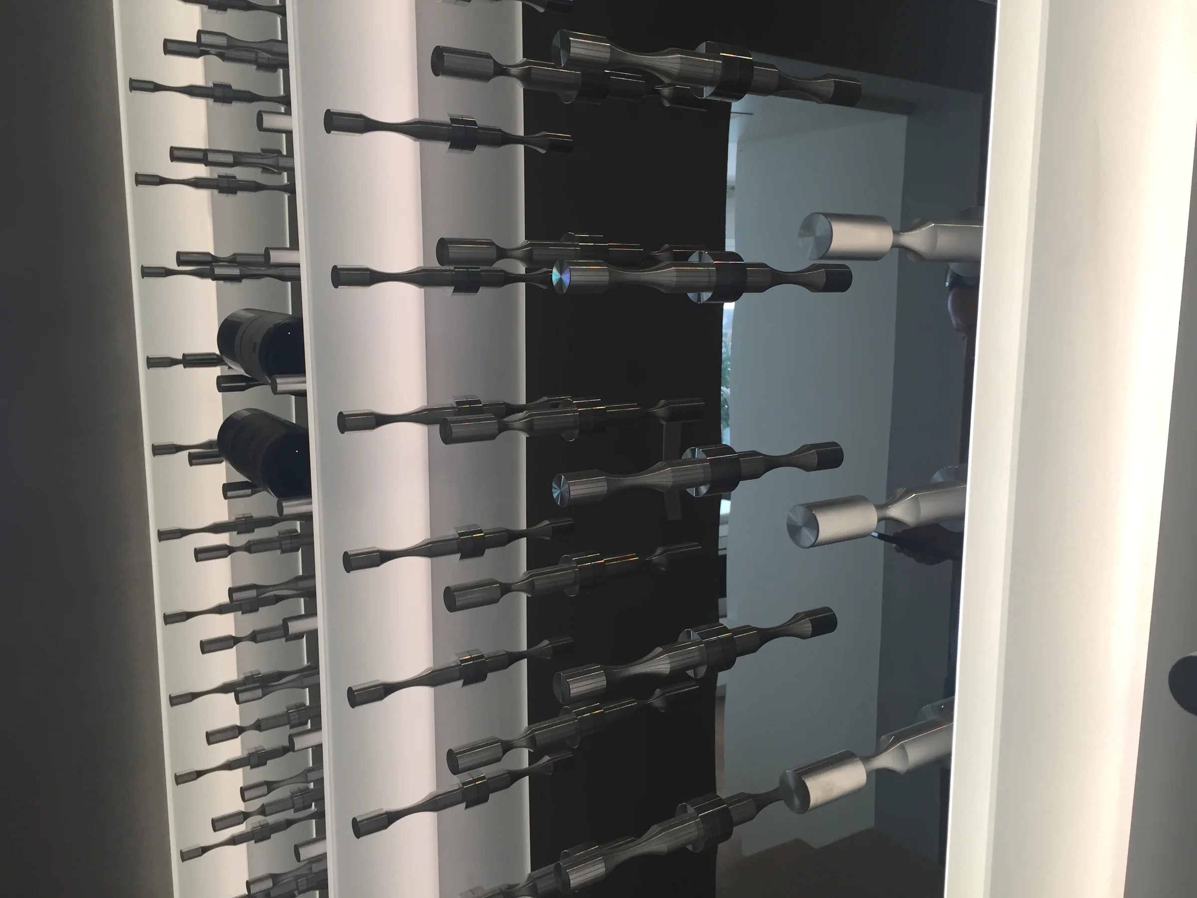 Illuminated wine display with custom metal bottle pegs