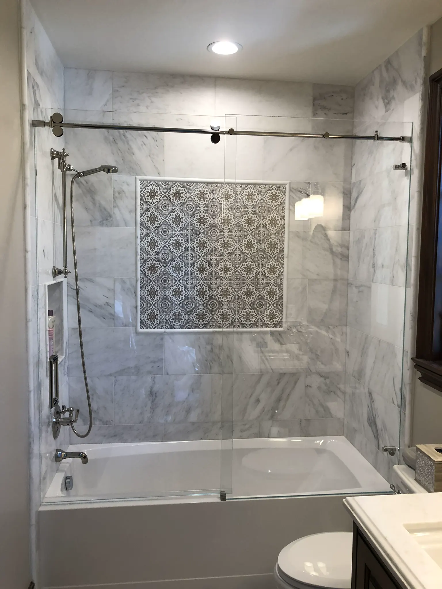 Frameless sliding glass shower door over a bathtub