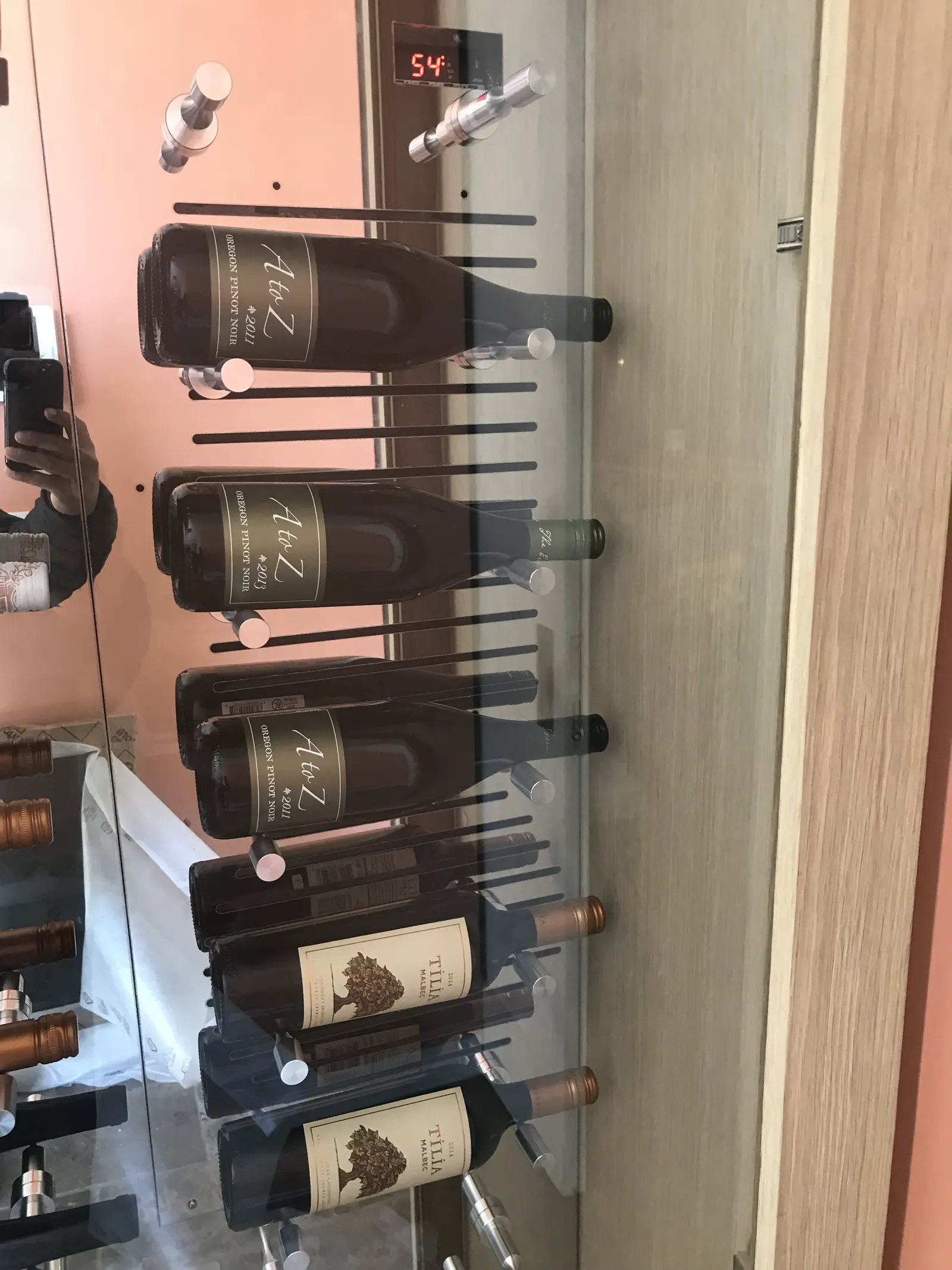 Wine bottles on metal pegs behind glass